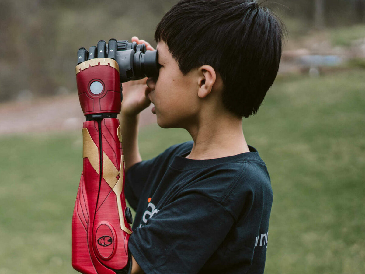 Boy using binoculars with his Iron Man Hero ARM raised